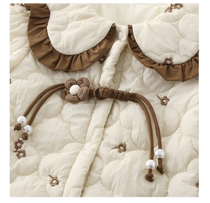 Détail du col Peter Pan avec matelassage en cœur et bouton fleur perle sur le body bébé