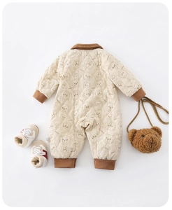 Detail of baby quilted romper with bear patterns, ribbed cuffs and plush bear bag