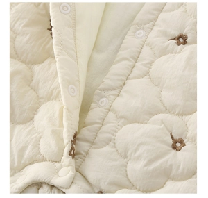 Gros plan d'une grenouillère pour bébé en tissu matelassé avec broderies florales brunes