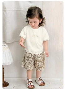 Dettaglio del set estivo per neonati con t-shirt crema con stampa animale e pantaloncini marroni