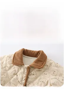 Detail view of baby quilted warm jacket with brown corduroy collar and cute bear patterns