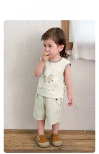 Detail of toddler summer outfit with cream vest and green striped shorts in a clean setting