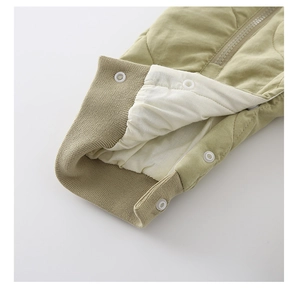 Detail of ribbed cuffs and dual zipper on quilted baby winter romper in olive green