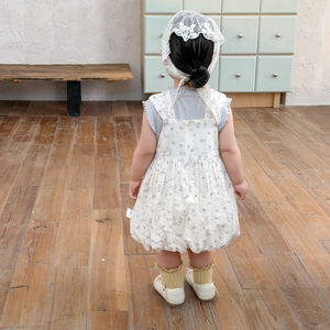Floral baby girl strap dress set with white lace headband in a minimalist home setting