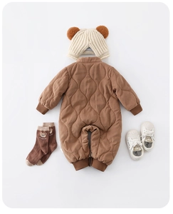 Flat lay of baby winter quilted romper with matching knit bear hat, socks, and shoes