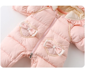 Detail of pink baby winter romper showing heart-shaped pockets and bow decorations