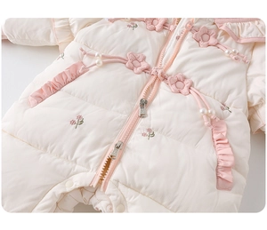 Close-up of quilted baby romper with 3D pink flower patches and pearl beads
