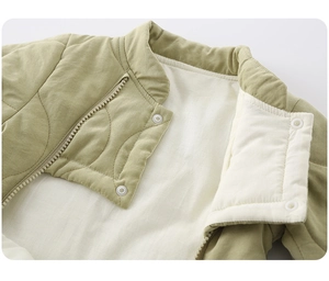 Detail of baby quilted jacket featuring wave stitching, zipper and button closure in mint green