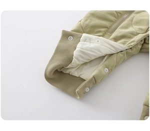 Detail of baby winter jumpsuit featuring green quilted fabric and soft cotton lining