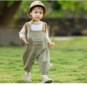 Detail of baby boy cotton overall set featuring green overalls and striped long sleeve top