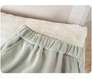 Detail view of light green corduroy pants with elastic waistband and side pockets
