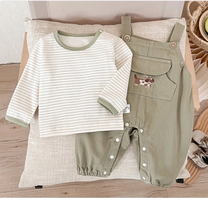 Detail of baby striped shirt and olive green overalls with embroidered puppy and wood buttons