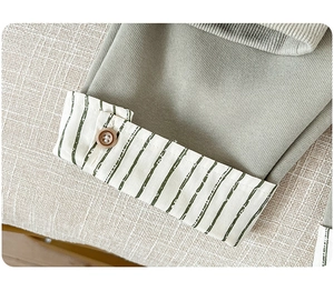 Detail of green knitted boy shirt with striped cuffs and brown resin button macro shot