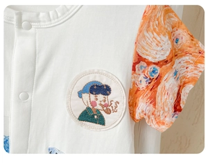 Detail of baby cotton romper with Van Gogh artist embroidery and orange print sleeves