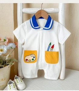 Detail of baby summer romper with navy collar and colorful painter pockets on white cotton