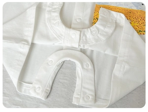 Detailed close-up of premium white cotton baby romper featuring snap button closures