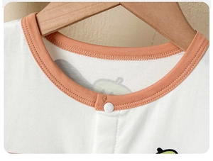 Détail de l'encolure d'un barboteuse bébé avec bordure orange et bouton-pression