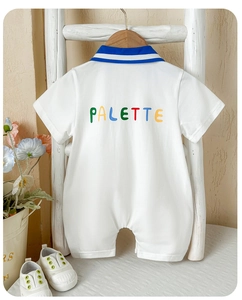 Detail of baby cotton romper featuring colorful PALETTE print and blue striped collar