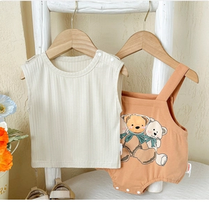 Détail de l'ensemble bébé avec haut beige côtelé et barboteuse orange à ours