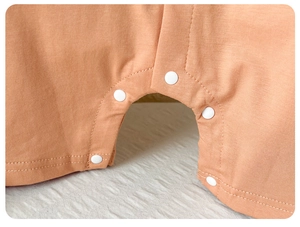 Vue détaillée des boutons-pression sur la grenouillère bébé en coton corail