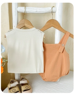 Détail d'une tenue d'été pour bébé avec haut rayé beige et body à bretelles en coton orange