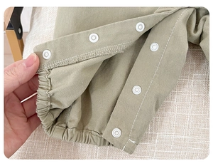 Close-up of cotton baby overalls with white snap buttons and elastic cuffs