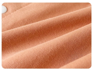 Détail macro du tissu en maille de coton rose orangé avec un bouton en résine mate blanche