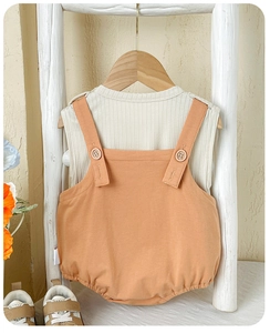 Détail de l'ensemble bébé deux pièces avec haut côtelé beige et barboteuse en coton orange
