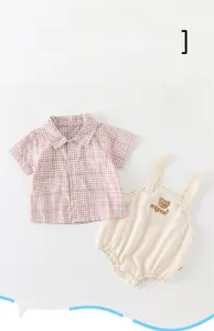 Detail von rosa kariertem Hemd und beigem Baby-Strampler mit niedlicher Bären-Stickerei