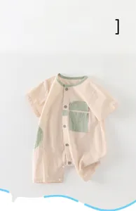 Detail view of cotton baby bodysuit with green contrast pocket and button-down closure