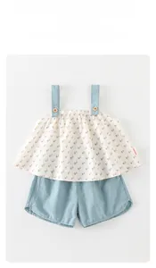 Dettaglio del top floreale neonata con pantaloncini blu che mostra texture e bottoni