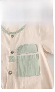 Close-up of baby romper collar and pocket with contrasting green trim and buttons