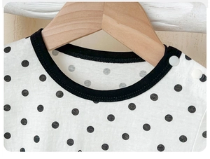 Detail of baby cotton bodysuit with polka dot pattern and shoulder snap buttons