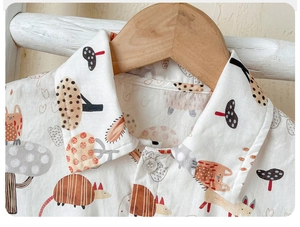 Detail of baby cotton onesie featuring cute forest mushroom and fox cartoon patterns