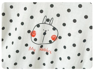 Detail of baby cotton bodysuit featuring black polka dots and a cute rabbit print
