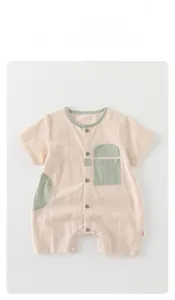 Detailed flat lay of pink cotton baby romper with snap buttons and green pocket accent