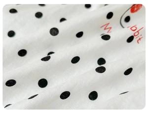 Close-up of soft white cotton fabric with black polka dots and red Rabbit pattern