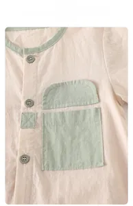 Detail of baby cotton linen romper with green piping, round neck and chest pocket