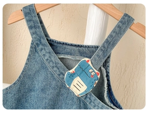 Détail d'une salopette en jean pour bébé avec écusson dinosaure et coutures de haute qualité