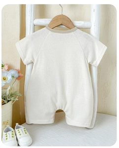 Rear view of light apricot baby short sleeve romper with brown trim and raglan sleeves