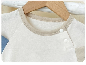 Close-up of baby romper collar with white resin buttons and smooth cotton stitching