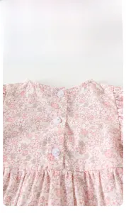 Détail de l'encolure d'un barboteuse fleurie bébé avec trois boutons blancs au dos