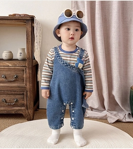 Détail d'un ensemble salopette en jean pour bébé avec dinosaure et chemise à rayures