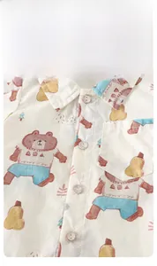 Close-up of baby cotton shirt featuring cute cartoon prints and natural wooden buttons