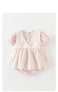 Détails rapprochés d'un barboteuse pour bébé avec broderie blanche et motif floral rose