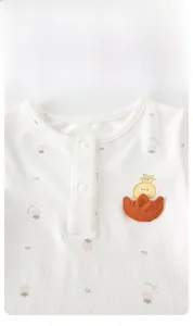 Détail de barboteuse bébé en coton nid d'abeille avec broderie tulipe et fraises