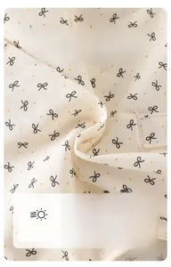 Close-up of soft cotton baby fabric with black bow print and orange polka dots