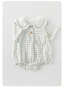 Detailed close-up of green checkered baby romper with wooden buttons and a Peter Pan collar