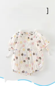 Close-up of white baby bodysuit with colorful polka dots and ruffled collar detail