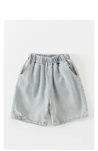 Detail of light blue denim shorts for boys featuring elastic waist and distressed hem